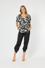 Load image into Gallery viewer, Hammock & Vine S/S shirt with shirred cuffs, high/low hem & button up front with V neck & collar in a stunning black ivy print on white.