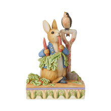 Load image into Gallery viewer, A figurine by Jim Shore of Peter Rabbit eating radishes next to a bird on a shovel. 14.5cm